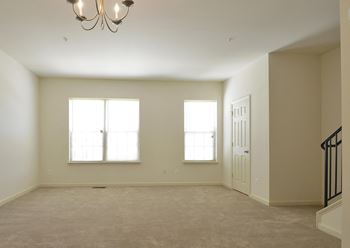 Empty room with a chandelier and two windows at The Pointe at Manorgreen Townhomes, Baltimore, MD 21220